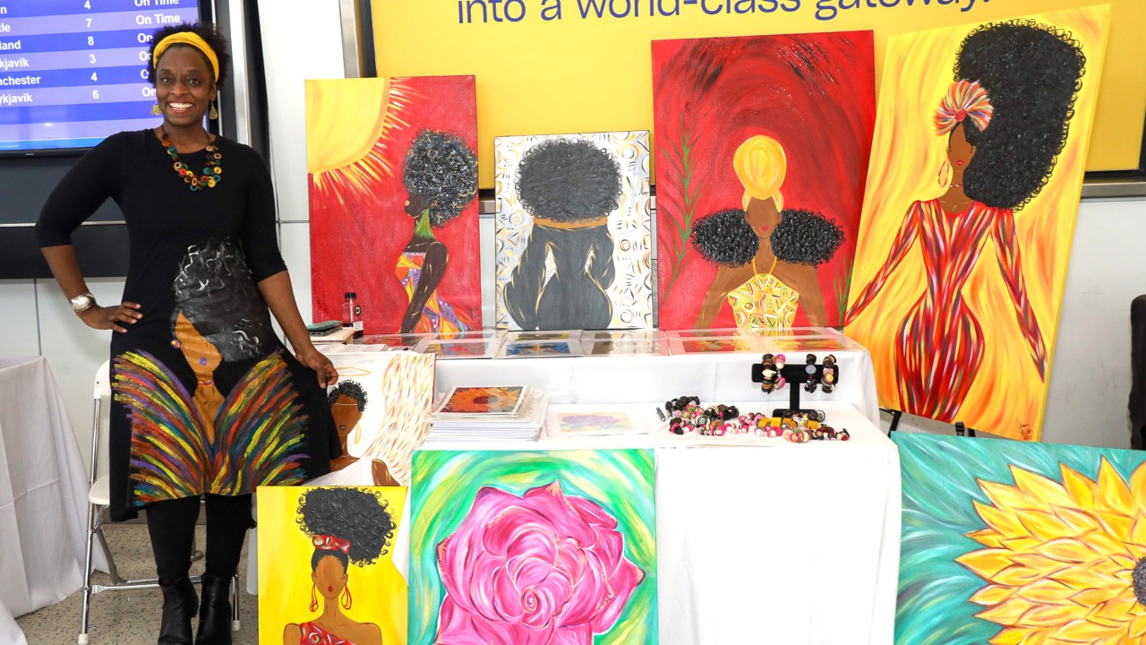 Woman smiles presenting art at the Taste of Africa Popup Market