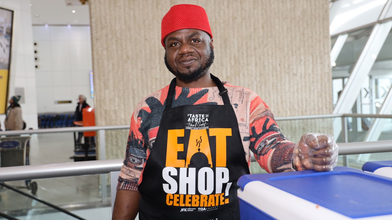 A man smiles at the camera wearing an apron