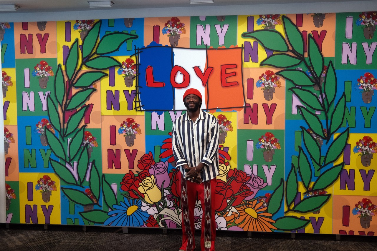 Artists stands in front of colorful mural