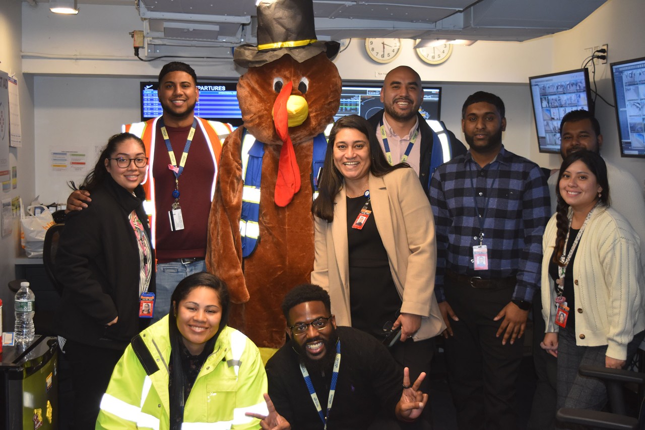 People smiling at camera with person in a turkey costume